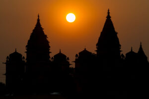 Silhouette of temple and cenotaphs at sunset by Betwa river, Orchha, India.